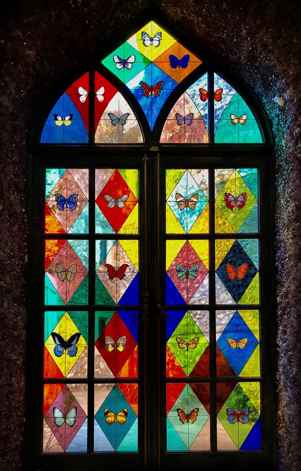 A single arched door filled with brightly coloured butterfly panels