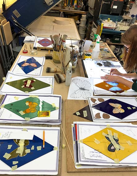Butterfly reference drawings and colour studies arranged across a studio workbench