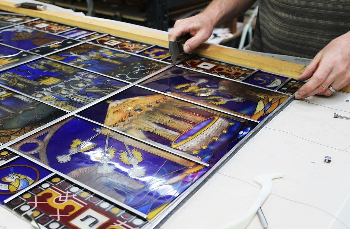The painted blue and red glass sections being assembled and leaded in the studio