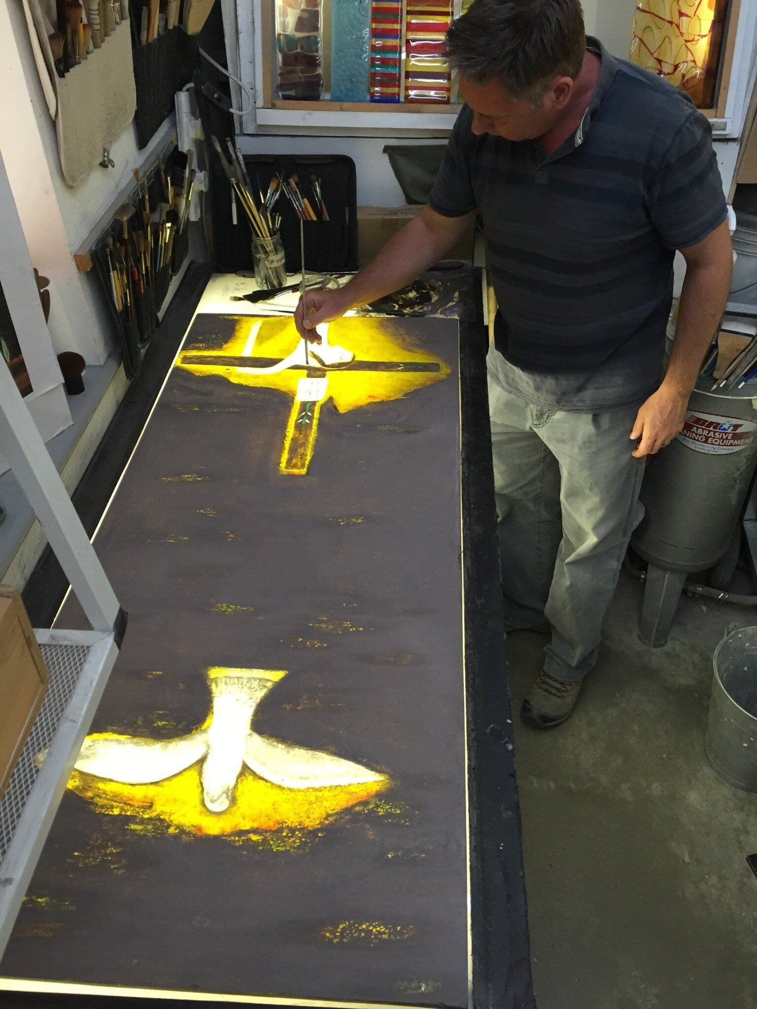 Richard Paton inspecting the completed fused-glass window illuminated on a studio lightbox