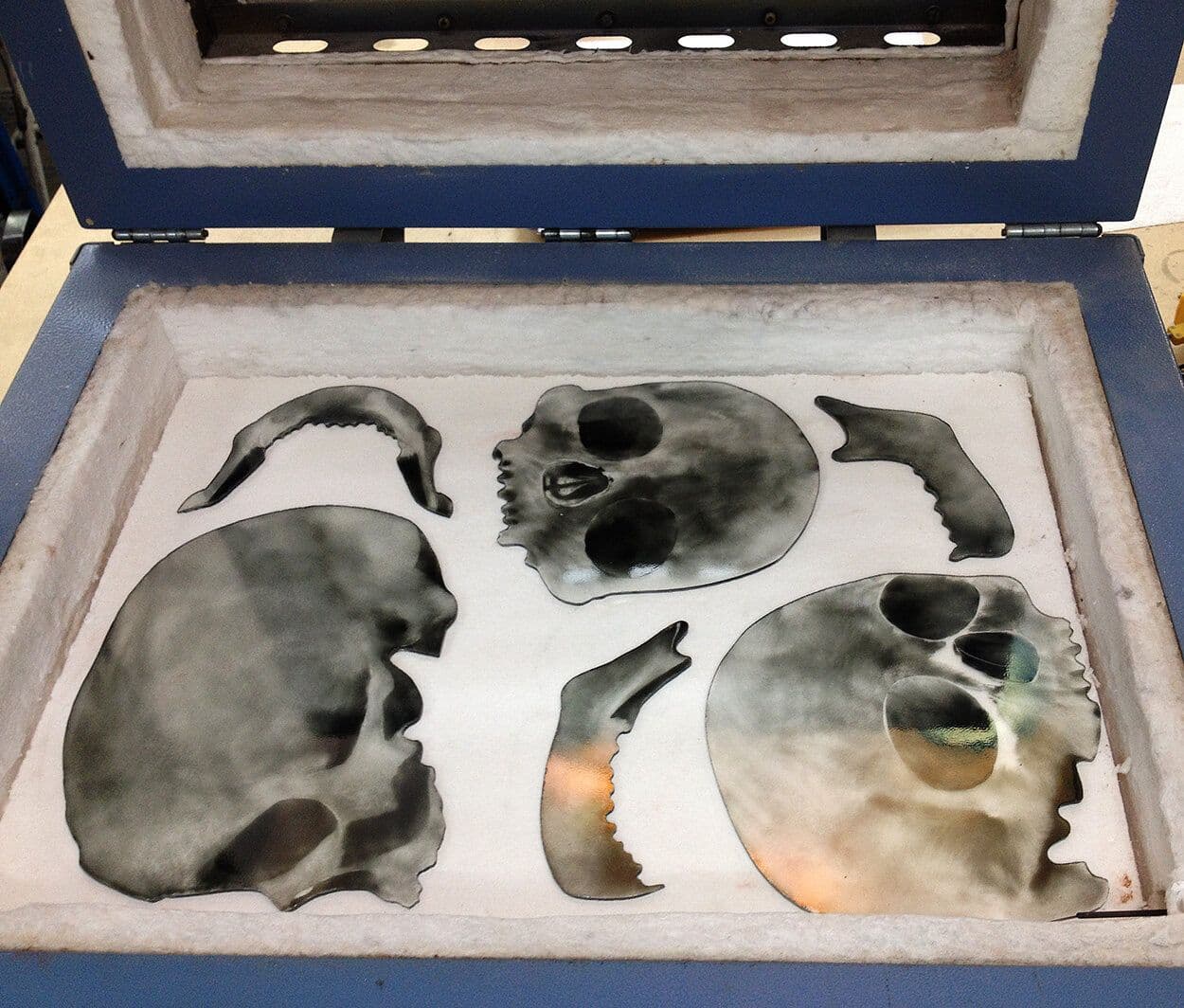 Painted skull glass pieces arranged inside the kiln