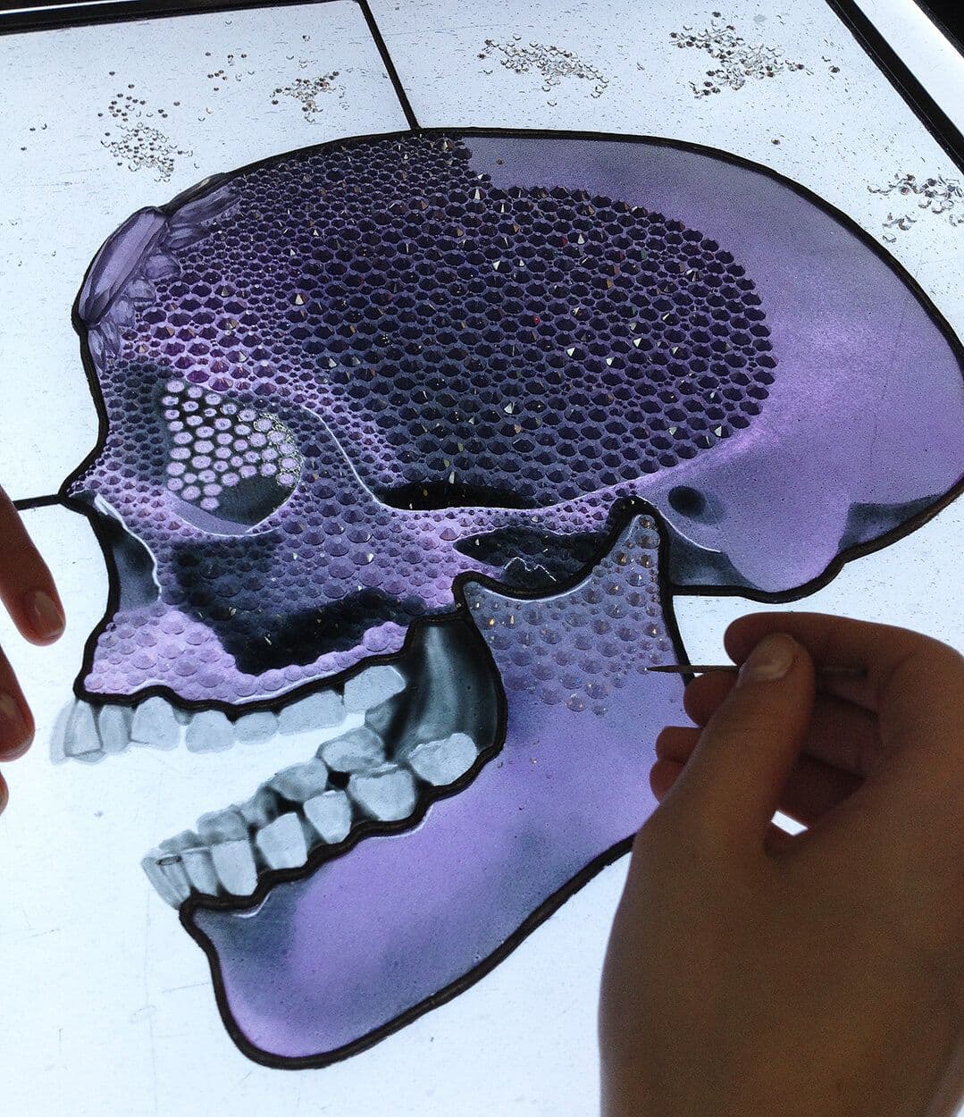 A purple profile skull being hand-painted on a light table