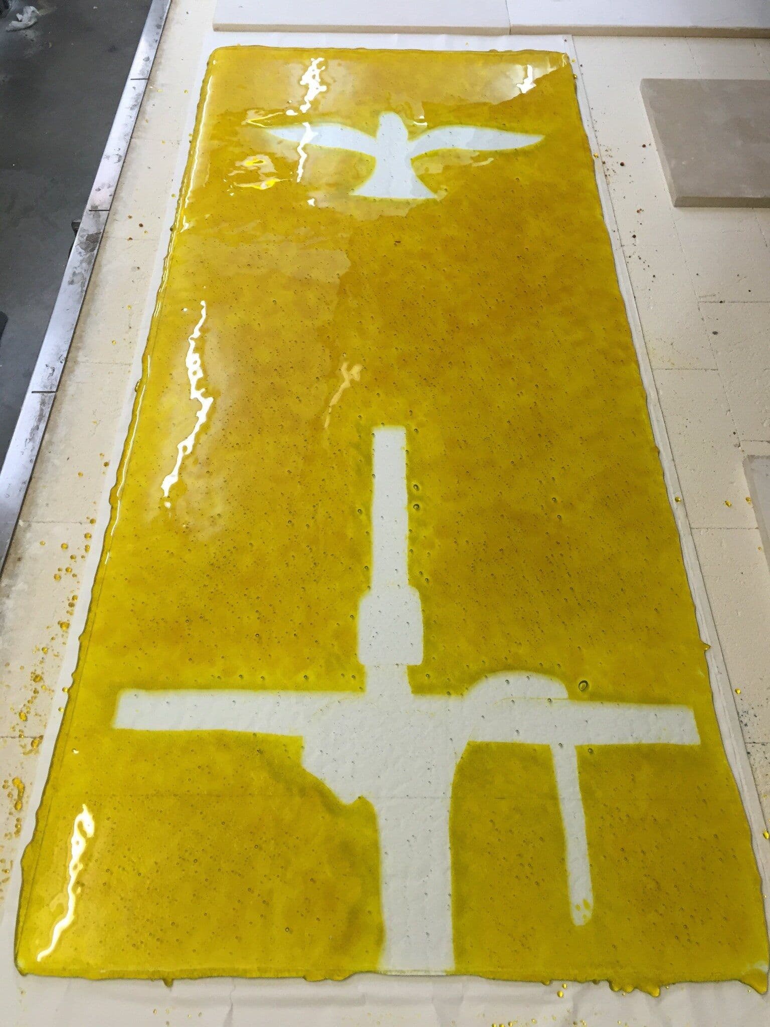 Full chapel window panel showing the crucifixion and dove against the yellow fused background