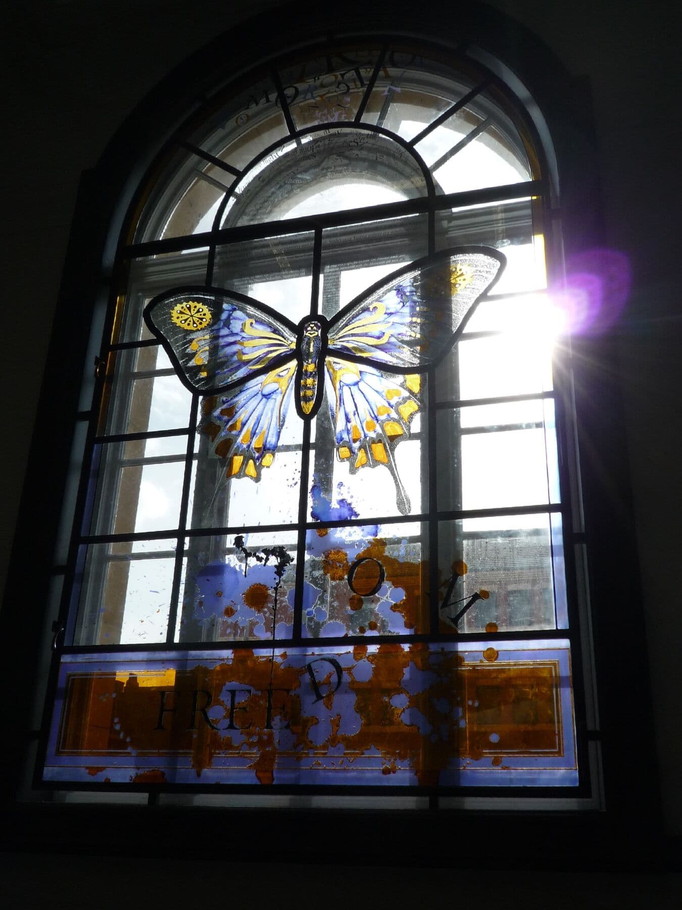 Completed arched stained-glass window with a butterfly motif