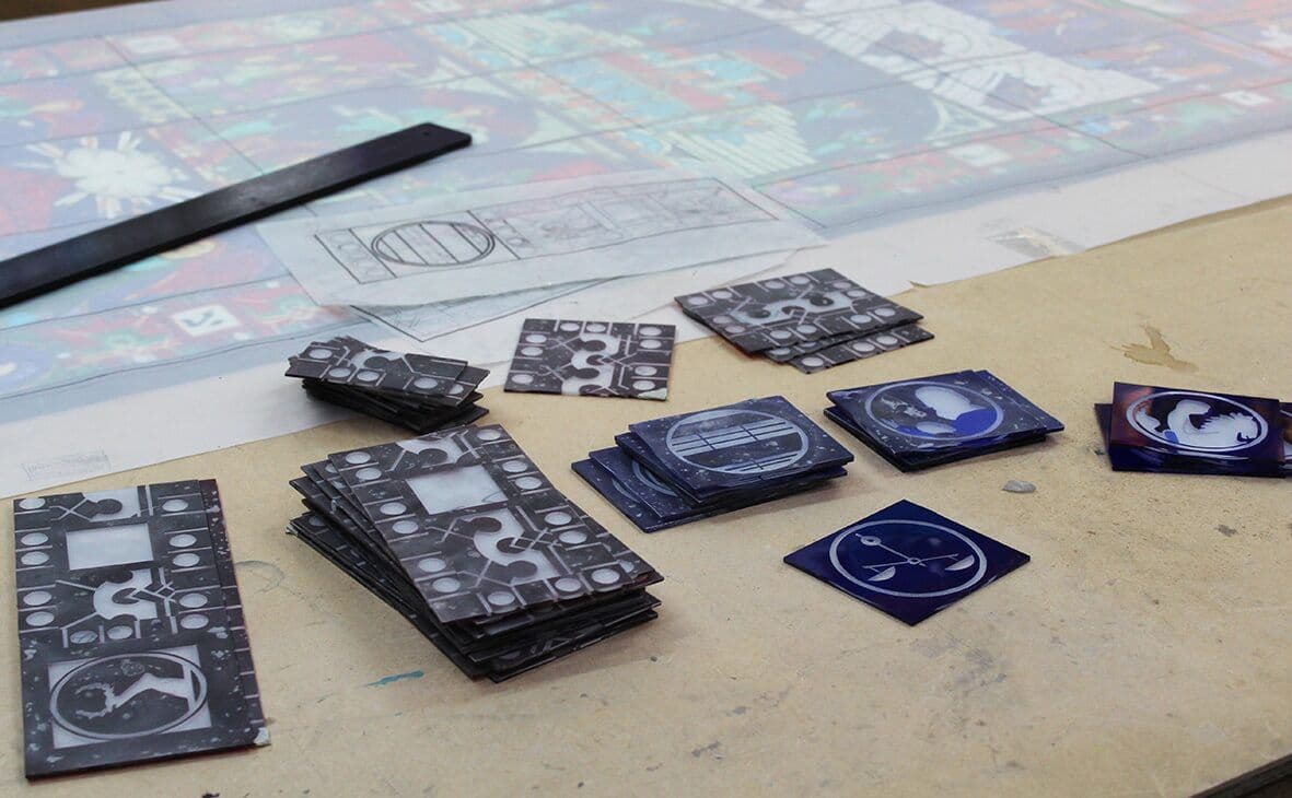 Painted and etched glass pieces arranged over the full-size drawing