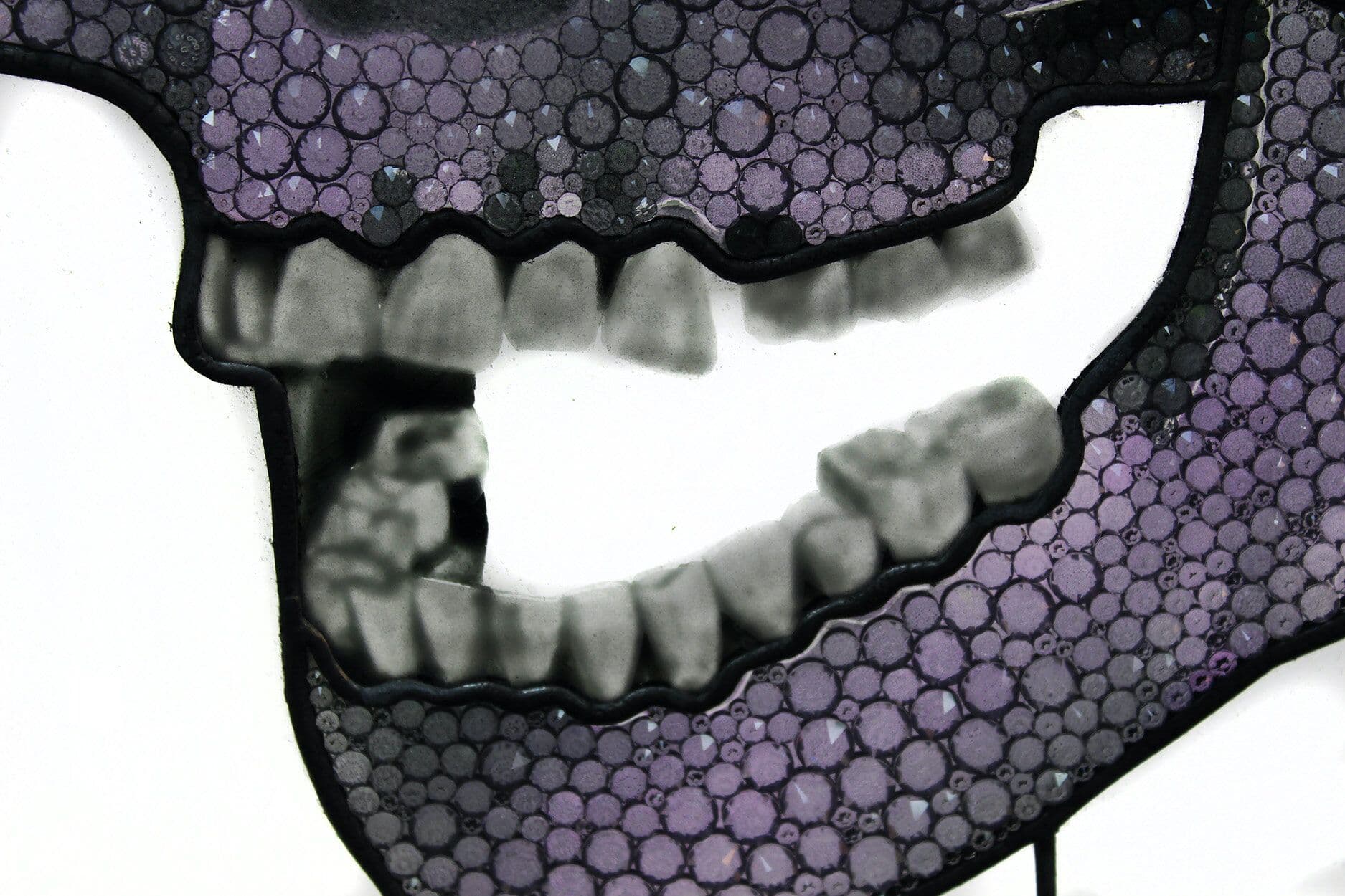 Close detail of the skull’s jaw, teeth and tightly packed circular glass and crystal elements