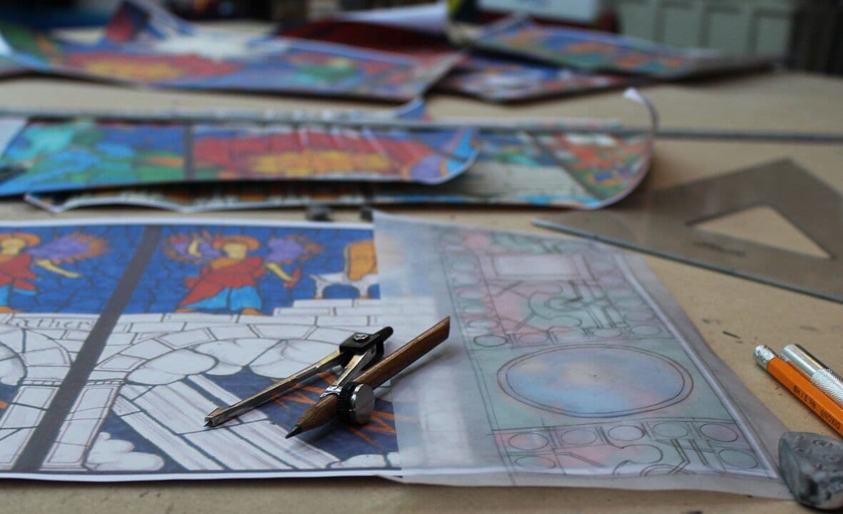 Detailed drawings and colour references for the synagogue window arranged on a studio workbench