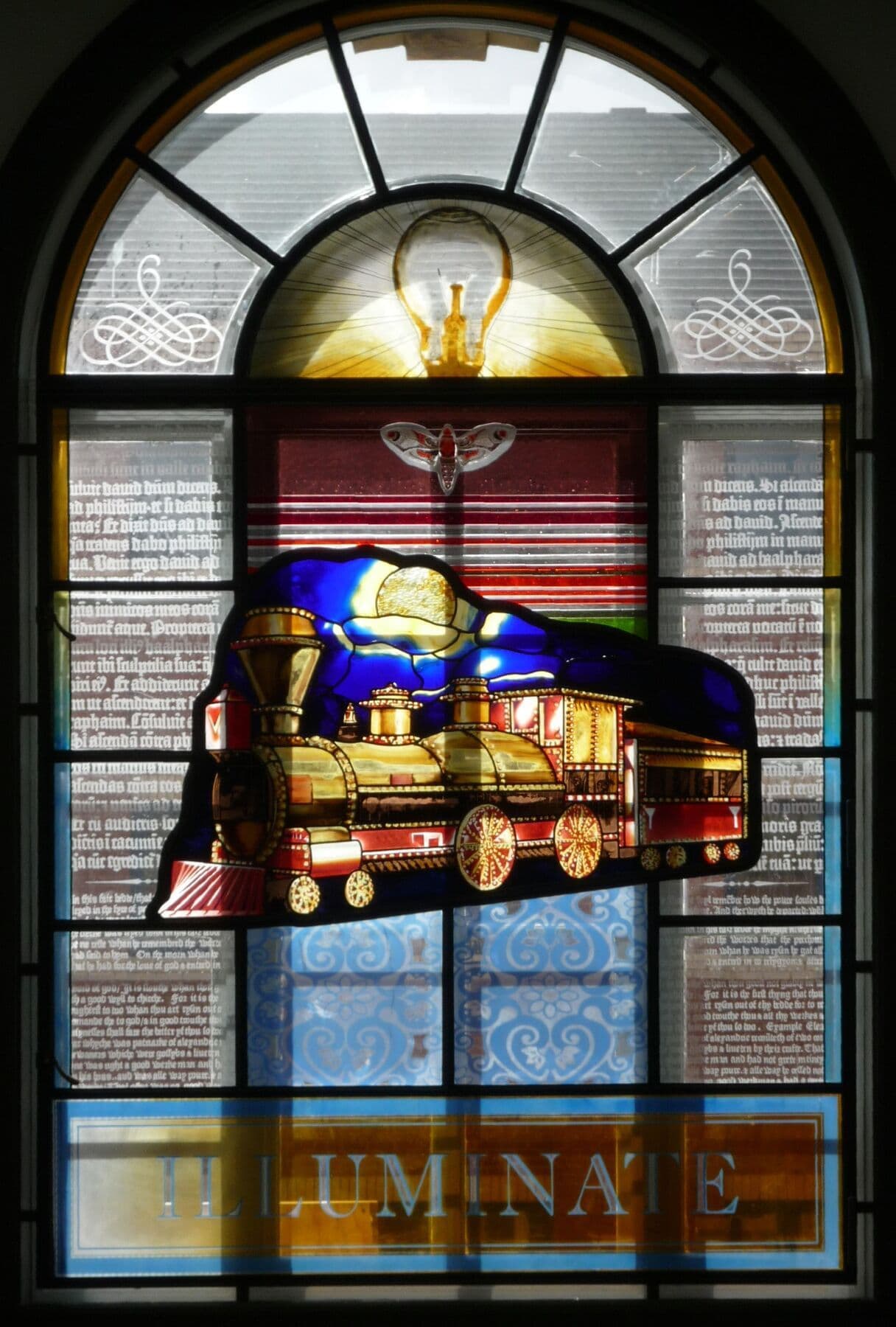 Completed arched stained-glass window featuring an illuminated train