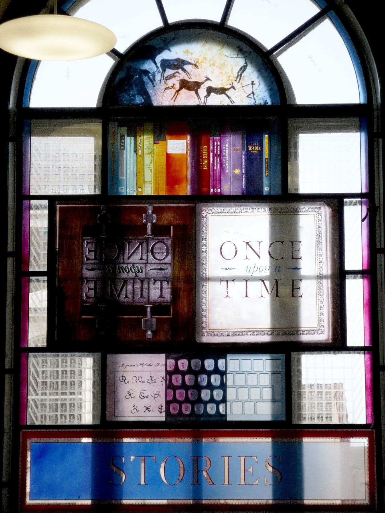 Tall stained-glass library window incorporating words and layered imagery