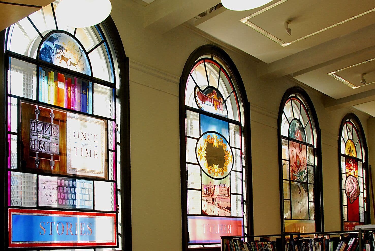 Three tall stained-glass windows seen inside Blackpool Central Library